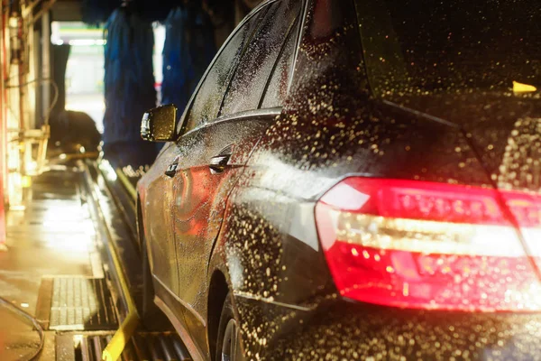 Car wash, zwarte auto in automatische Autowassen, roterende borstel van rood en blauw. Wassen voertuig. — Stockfoto