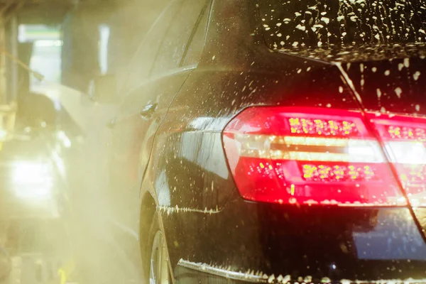 Car wash, zwarte auto in automatische Autowassen, roterende borstel van rood en blauw. Wassen voertuig. — Stockfoto