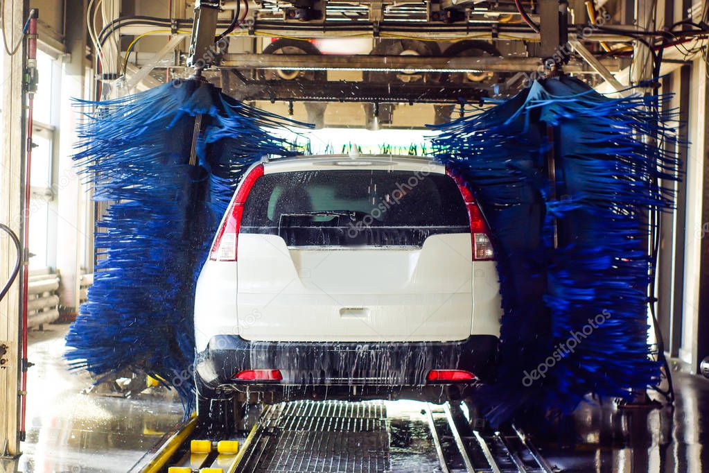Lavado de autos, coche negro en lavado automático de autos, cepillo rojo y azul giratorio