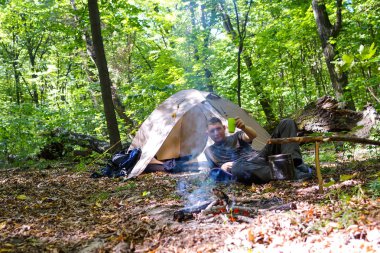Bir şenlik ateşi ve ormandaki bir turist çadır, çadır turist dinleniyor.