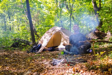 Bir şenlik ateşi ve ormandaki bir turist çadır, çadır turist dinleniyor.