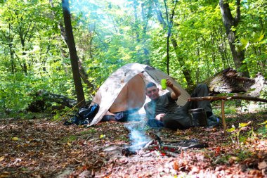 Bir şenlik ateşi ve ormandaki bir turist çadır, çadır turist dinleniyor.