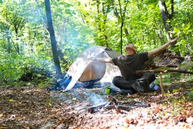 Bir şenlik ateşi ve ormandaki bir turist çadır, çadır turist dinleniyor.