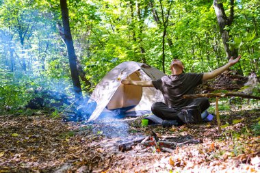 Bir şenlik ateşi ve ormandaki bir turist çadır, çadır turist dinleniyor.