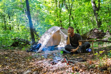 Bir şenlik ateşi ve ormandaki bir turist çadır, çadır turist dinleniyor.