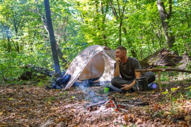 Bir şenlik ateşi ve ormandaki bir turist çadır, çadır turist dinleniyor.