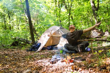 Bir şenlik ateşi ve ormandaki bir turist çadır, çadır turist dinleniyor.