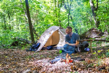 Bir şenlik ateşi ve ormandaki bir turist çadır, çadır turist dinleniyor.