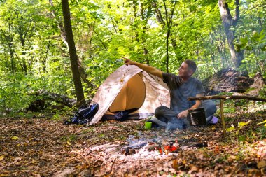 Bir şenlik ateşi ve ormandaki bir turist çadır, çadır turist dinleniyor.