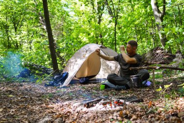 Bir şenlik ateşi ve ormandaki bir turist çadır, çadır turist dinleniyor.