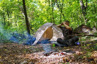 Bir şenlik ateşi ve ormandaki bir turist çadır, çadır turist dinleniyor.