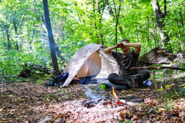 Bir şenlik ateşi ve ormandaki bir turist çadır, çadır turist dinleniyor.
