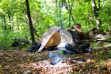 Bir şenlik ateşi ve ormandaki bir turist çadır, çadır turist dinleniyor.