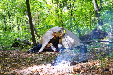 Bir şenlik ateşi ve ormandaki bir turist çadır, çadır turist dinleniyor.