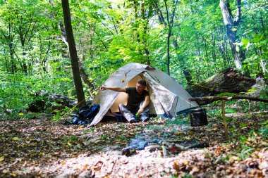 Bir şenlik ateşi ve ormandaki bir turist çadır, çadır turist dinleniyor.