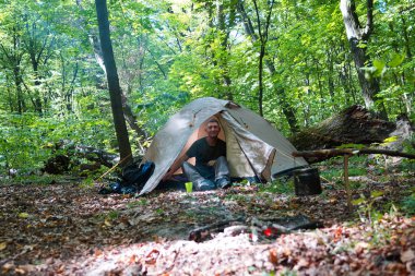 Bir şenlik ateşi ve ormandaki bir turist çadır, çadır turist dinleniyor.