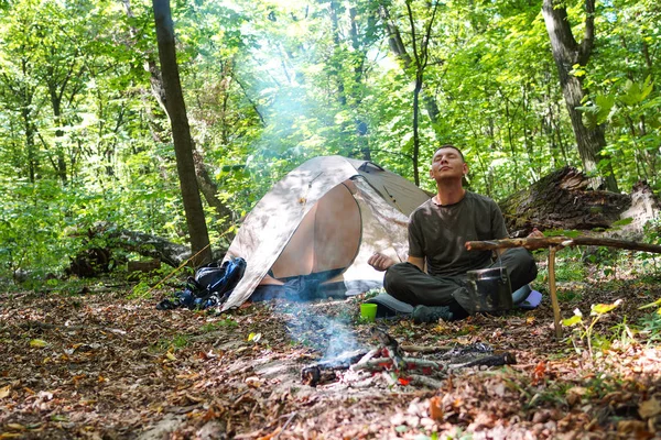 Bir şenlik ateşi ve ormandaki bir turist çadır, çadır turist dinleniyor.
