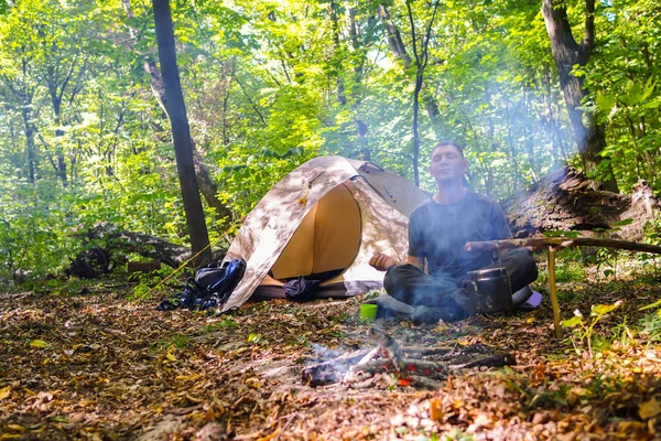 Bir şenlik ateşi ve ormandaki bir turist çadır, çadır turist dinleniyor.