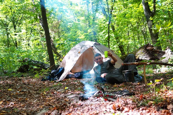 Bir şenlik ateşi ve ormandaki bir turist çadır, çadır turist dinleniyor.