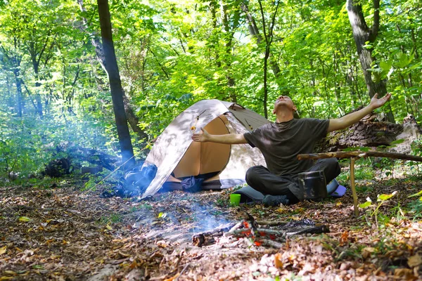 Bir şenlik ateşi ve ormandaki bir turist çadır, çadır turist dinleniyor.