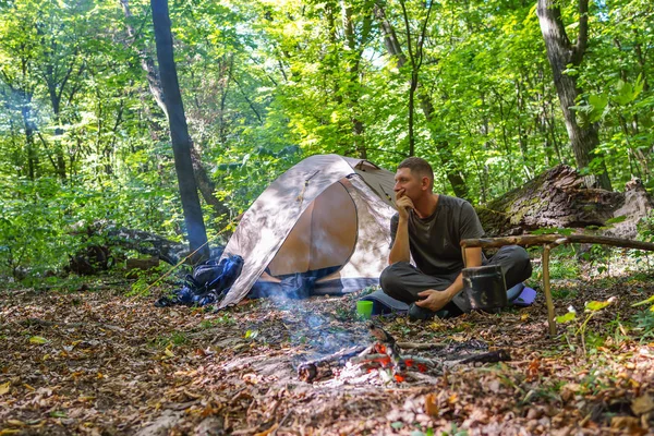 Bir şenlik ateşi ve ormandaki bir turist çadır, çadır turist dinleniyor.