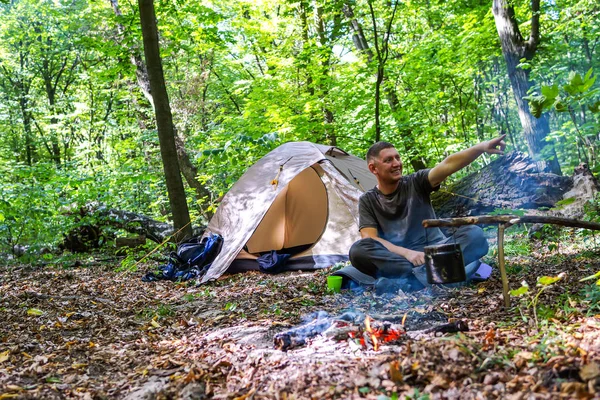 Bir şenlik ateşi ve ormandaki bir turist çadır, çadır turist dinleniyor.