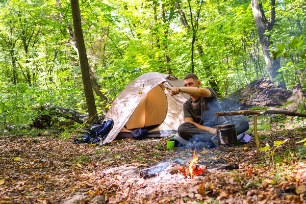 Bir şenlik ateşi ve ormandaki bir turist çadır, çadır turist dinleniyor.