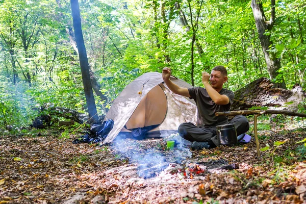 Bir şenlik ateşi ve ormandaki bir turist çadır, çadır turist dinleniyor.
