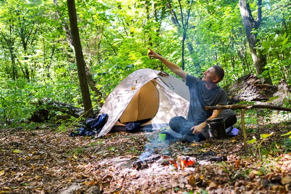 Bir şenlik ateşi ve ormandaki bir turist çadır, çadır turist dinleniyor.