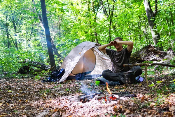Bir şenlik ateşi ve ormandaki bir turist çadır, çadır turist dinleniyor.