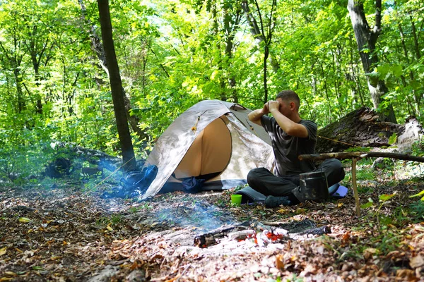 Bir şenlik ateşi ve ormandaki bir turist çadır, çadır turist dinleniyor.