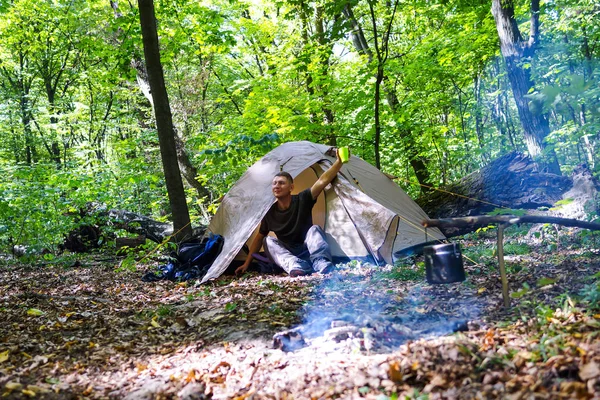 Een vreugdevuur en een toeristische tent in het forest, de toerist is rust in de buurt van de tent. — Stockfoto
