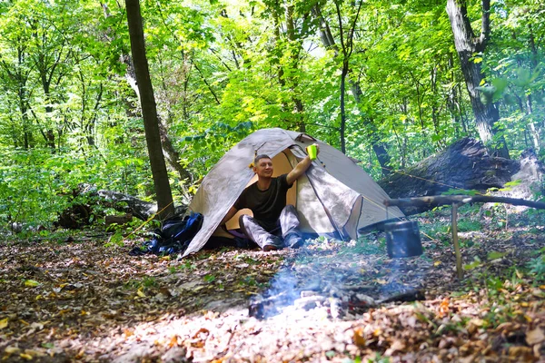 Bir şenlik ateşi ve ormandaki bir turist çadır, çadır turist dinleniyor.