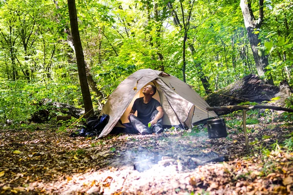 Bir şenlik ateşi ve ormandaki bir turist çadır, çadır turist dinleniyor.
