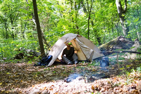 Bir şenlik ateşi ve ormandaki bir turist çadır, çadır turist dinleniyor.