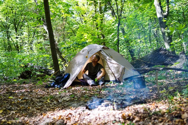 Bir şenlik ateşi ve ormandaki bir turist çadır, çadır turist dinleniyor.