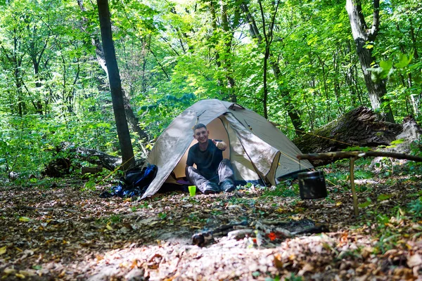 Bir şenlik ateşi ve ormandaki bir turist çadır, çadır turist dinleniyor.