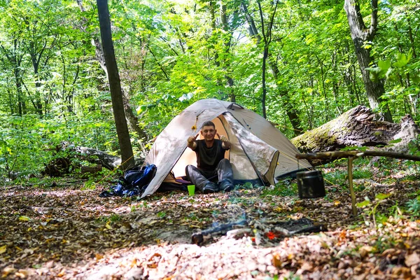 Bir şenlik ateşi ve ormandaki bir turist çadır, çadır turist dinleniyor.