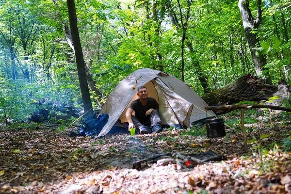 Een vreugdevuur en een toeristische tent in het forest, de toerist is rust in de buurt van de tent. — Stockfoto