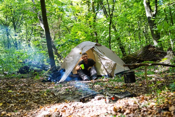 Bir şenlik ateşi ve ormandaki bir turist çadır, çadır turist dinleniyor.