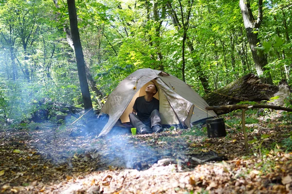Bir şenlik ateşi ve ormandaki bir turist çadır, çadır turist dinleniyor.