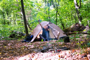 Bir şenlik ateşi ve ormandaki bir turist çadır, çadır turist dinleniyor.