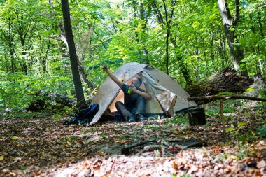 Bir şenlik ateşi ve ormandaki bir turist çadır, çadır turist dinleniyor.