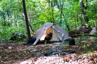Bir şenlik ateşi ve ormandaki bir turist çadır, çadır turist dinleniyor.