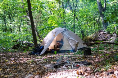 Bir şenlik ateşi ve ormandaki bir turist çadır, çadır turist dinleniyor.