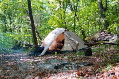 Bir şenlik ateşi ve ormandaki bir turist çadır, çadır turist dinleniyor.