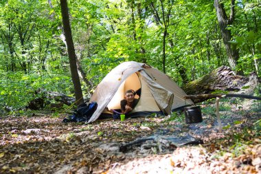 Bir şenlik ateşi ve ormandaki bir turist çadır, çadır turist dinleniyor.