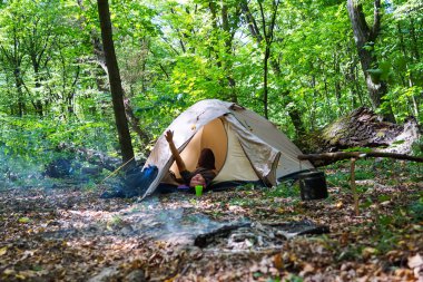 Bir şenlik ateşi ve ormandaki bir turist çadır, çadır turist dinleniyor.