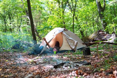 Bir şenlik ateşi ve ormandaki bir turist çadır, çadır turist dinleniyor.