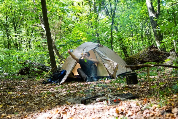 Bir şenlik ateşi ve ormandaki bir turist çadır, çadır turist dinleniyor.